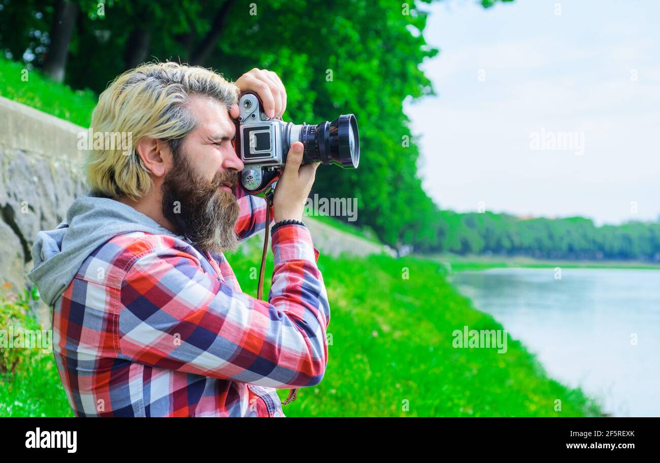 Mann Reisende macht Fotos in der Nähe des Flusses. Reisen und Tourismus. Männlicher Fotograf mit Digitalkamera. Stockfoto