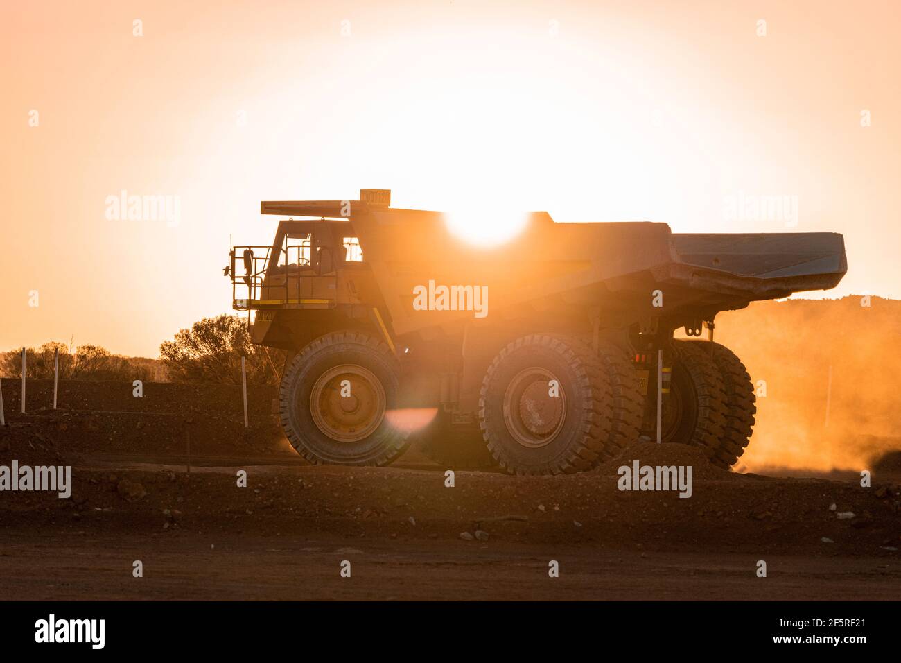 Muldenkipper, der bei Sonnenuntergang auf der Haul Road im Tagebaugebiet fährt. Stockfoto