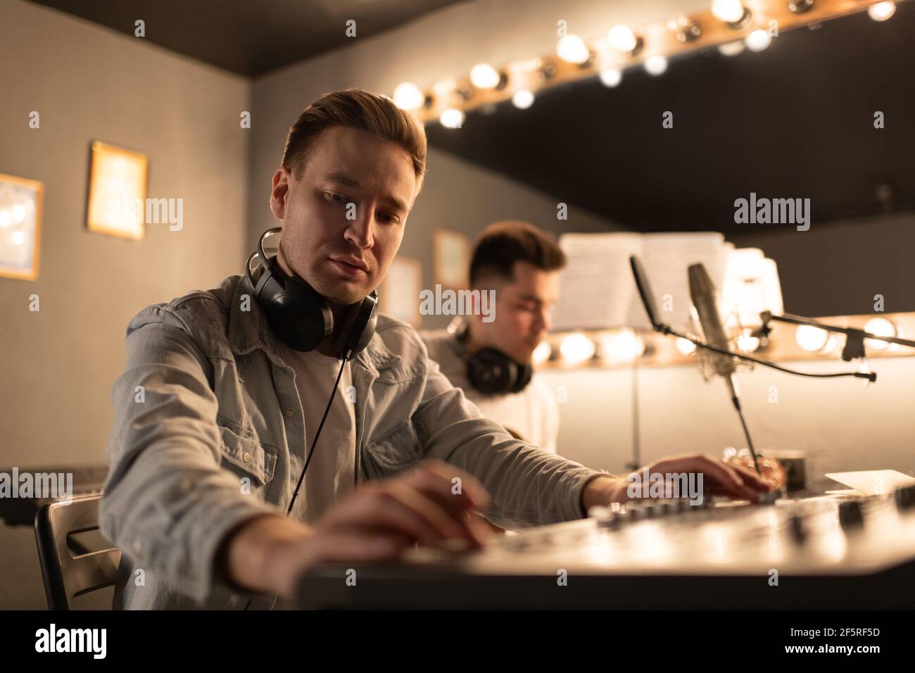 Fokussierter Musiker mit Soundboard in der Nähe von Kollegen Stockfoto