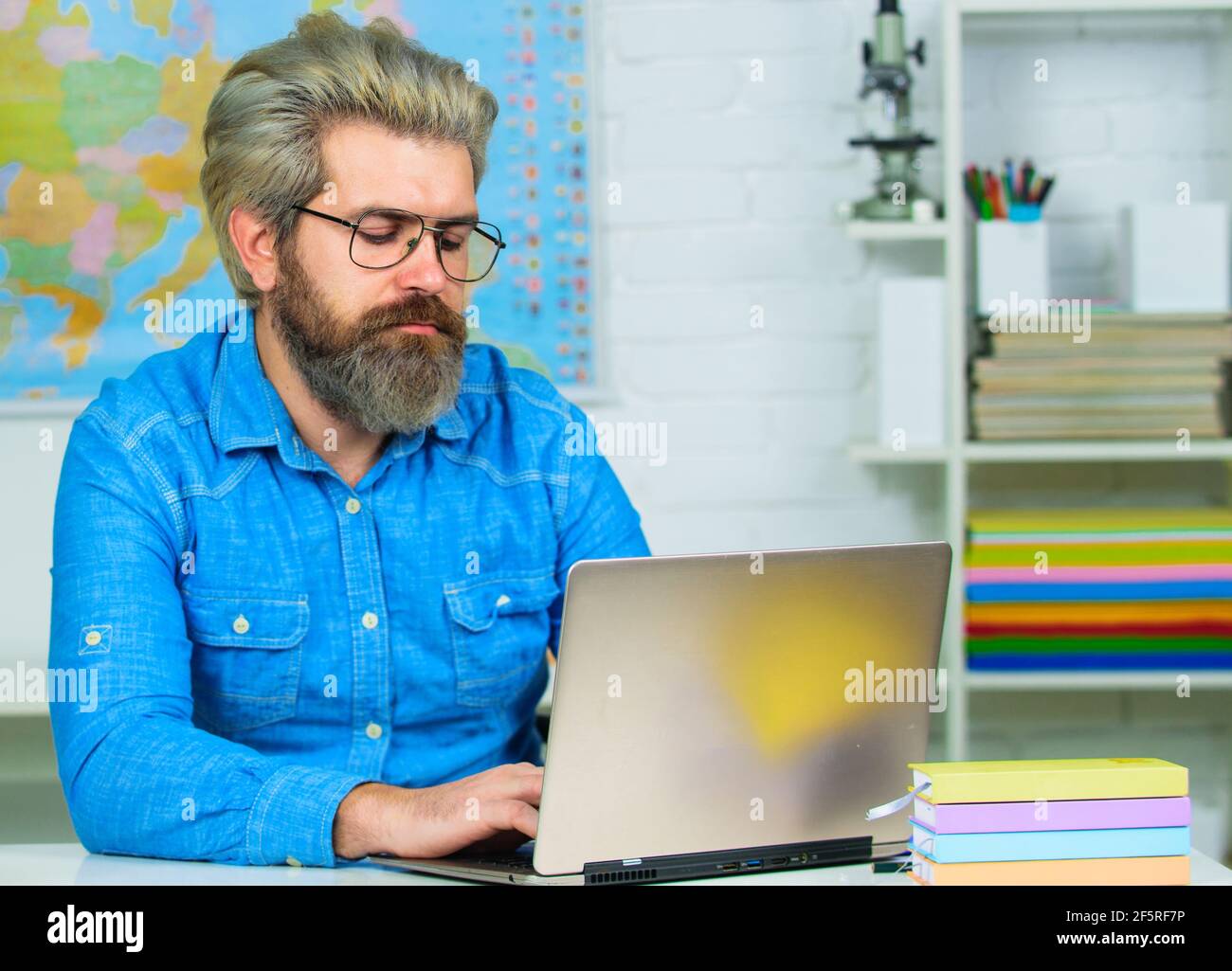 Serious Student mit Notebook studieren in der Hochschule. Bärtiger Lehrer mit Laptop im Klassenzimmer. Stockfoto