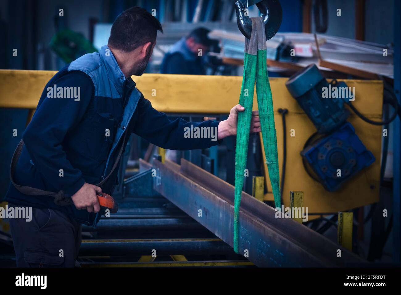 Mann, der Stahlträger auf die Schneidemaschine mit Kran setzt Stockfoto