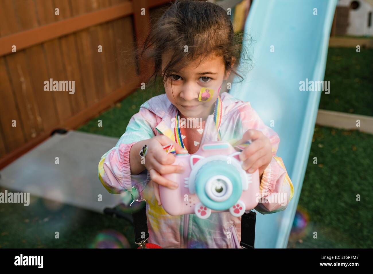 Mädchen spielt mit Blase Maschine Kamera im Hinterhof Stockfoto