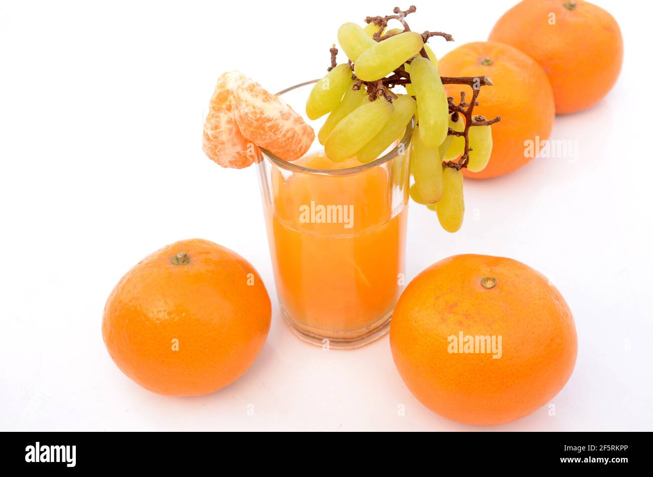 Ein Glas gesunder Mandarinensaft mit reifen grünen Trauben Isoliert auf weißem Hintergrund Stockfoto
