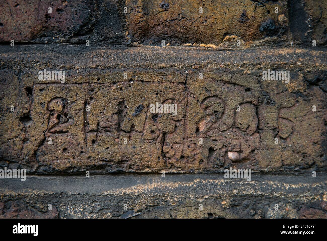 Schnitzereien von Zahlen, Buchstaben und Daten, die in das Mauerwerk einer Wand, die eine Seite der Myddelton Passage in Islington, Nord-London, umraht, geguckt wurden. Der merkwürdige Fall von Vandalismus wurde höchstwahrscheinlich von 19th und 20th Polizeibeamten ausgeführt, die beauftragt wurden, den Durchgang nachts zu bewachen. Bilddatum: Freitag, 26. März 2021. Stockfoto