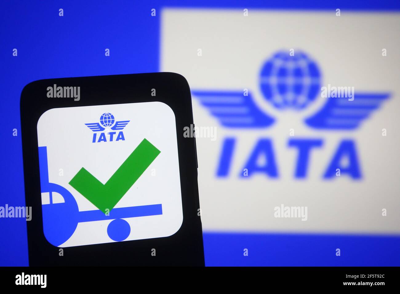 In dieser Abbildung wird das Travel Pass Symbol einer mobilen Anwendung der IATA (International Air Transport Association) auf einem Smartphone-Bildschirm vor dem IATA-Logo angezeigt. Der Travel Pass ist ein neuer digitaler „COVID-19 Impfpass“ der IATA (International Air Transport Association), mit dem Reisende ihre verifizierten Zertifizierungen für COVID-19-Tests oder COVID-19-Impfnachweise speichern und verwalten können. Stockfoto