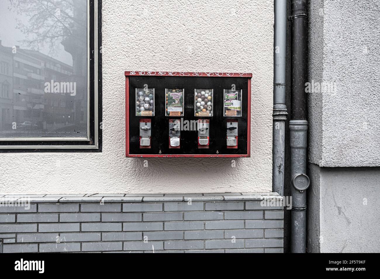 Bonn, NRW, Deutschland, 03 23 2021, Gummiballmaschine an einer Wand befestigt, Abwasserrohr und Reflexionen im Fenster Stockfoto