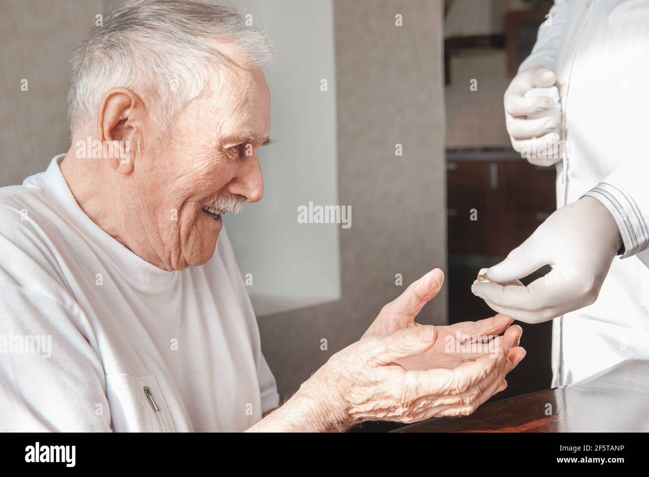 Pflegeheim, ein geriatrischer Arzt gibt einem älteren Patienten eine Flasche Pillen. Vitamin-Prävention von Covid-19 bei älteren Patienten. Vorbereitung für die Impfung Stockfoto