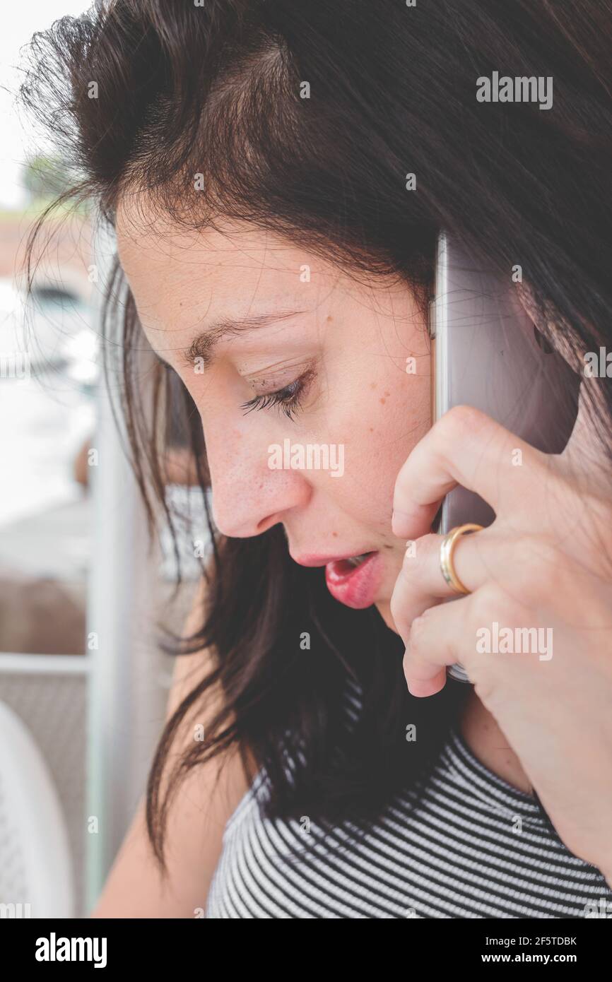 Brunette Mädchen mit einem gestreiften T-Shirt reden auf dem Handy. Foto im Retro-Stil. Stockfoto