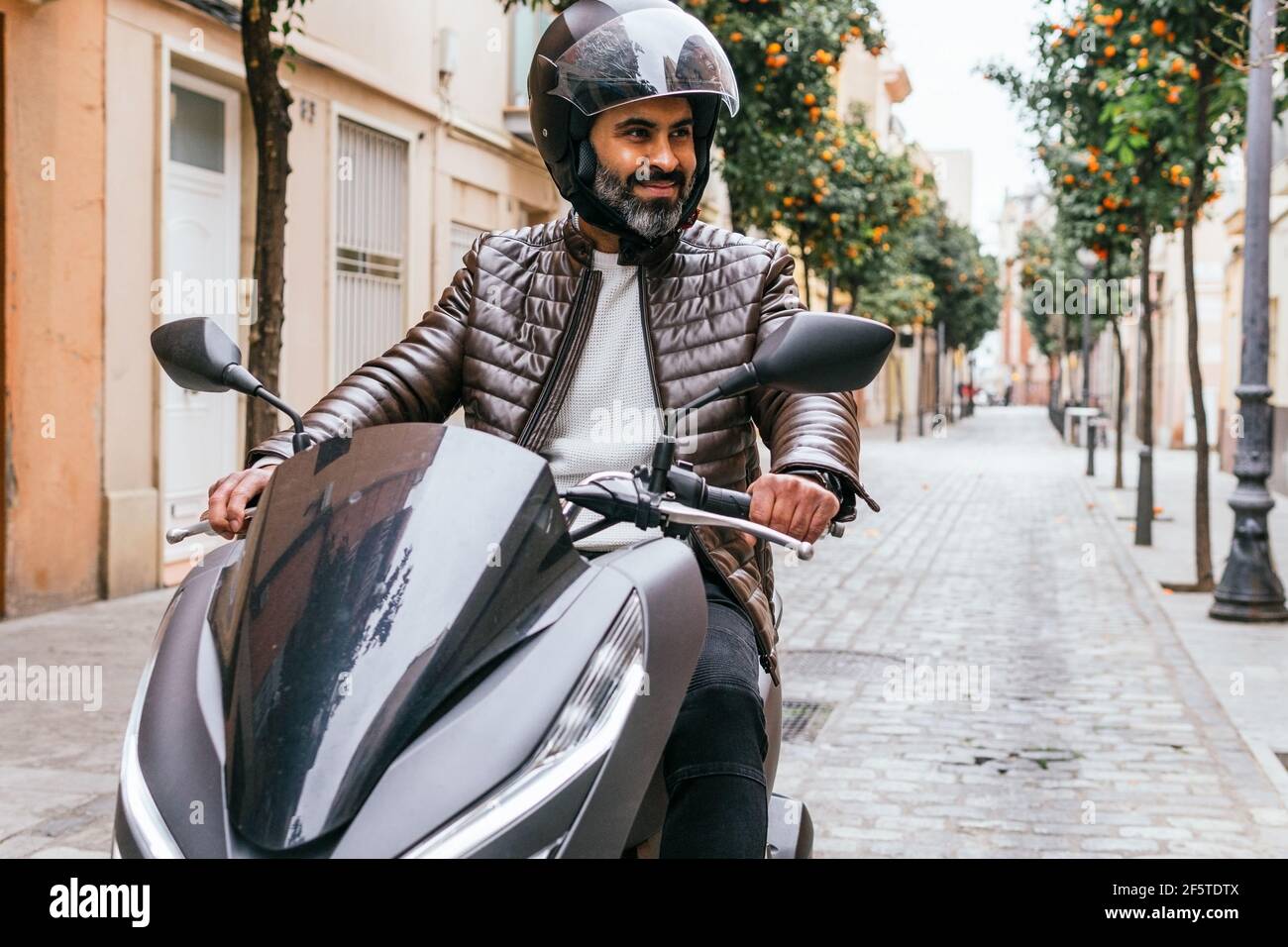 Brutal ethnischen männlichen Biker im Helm fahren zeitgenössische Motorrad während Sieht so aus wie in der Stadt Stockfoto