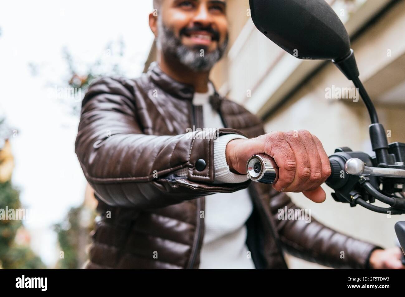 Von unten abgeschnitten von brutalen ethnischen männlichen Biker fahren zeitgenössisch Motorrad, während Sie sich in der Stadt nach vorne freuen Stockfoto