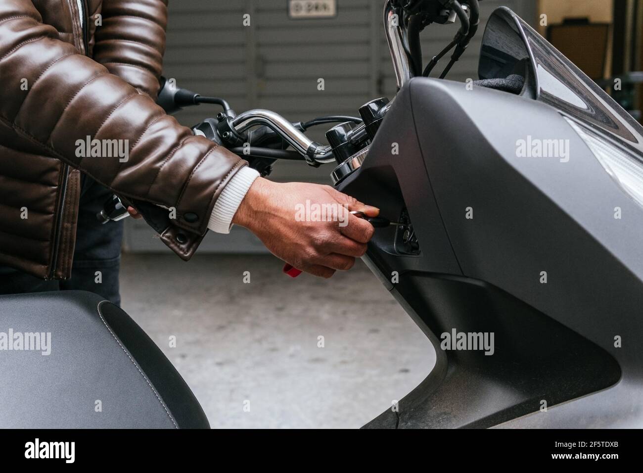 Crop unkenntlich männlichen Motorradfahrer in Lederjacke Einstecken Zündschlüssel In moderne Fahrrad in der Stadt Stockfoto