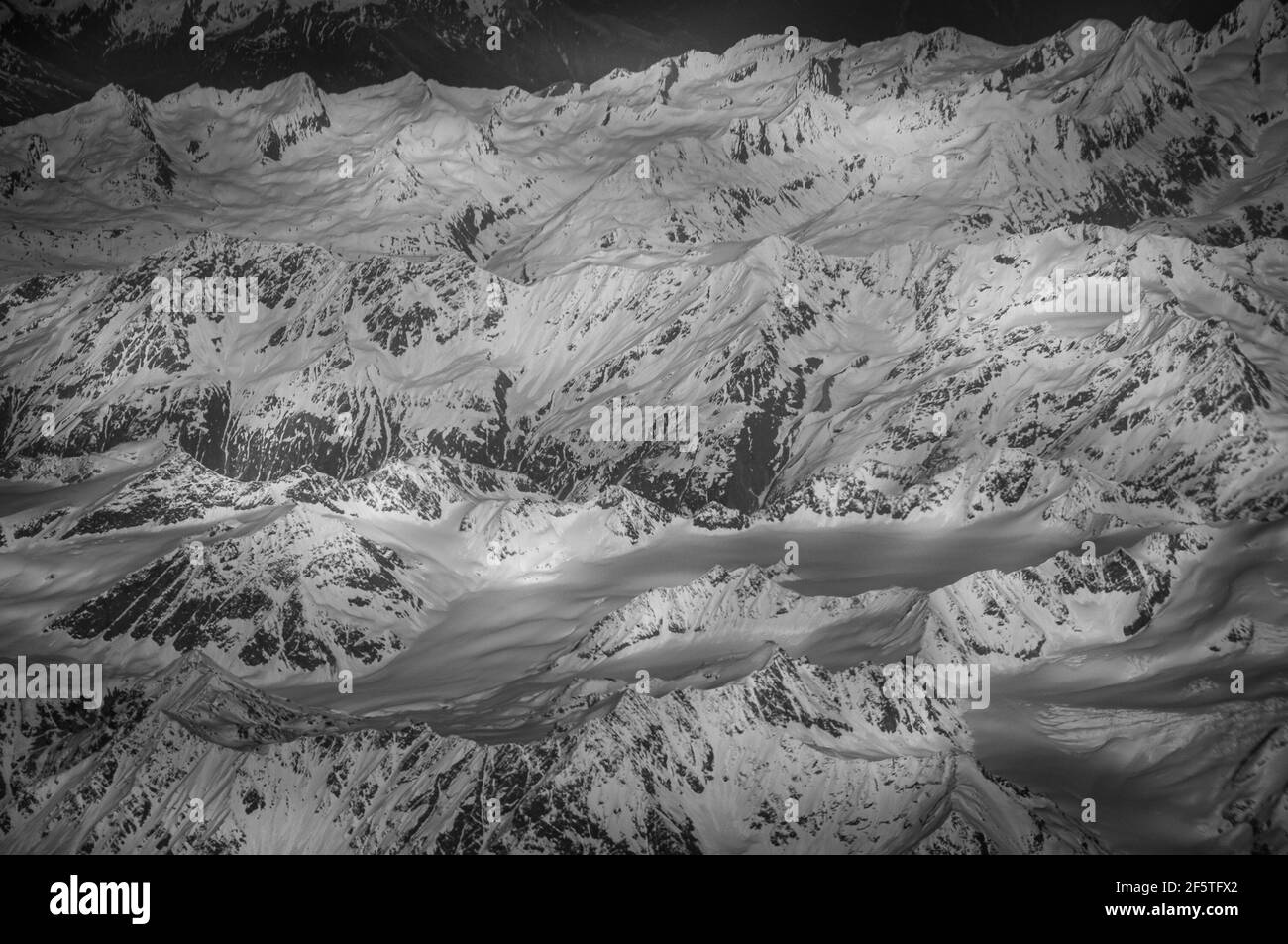 Schwarz-Weiß-Effekt von Gletschern und schneebedeckten Gipfeln der Alpen vom Flugzeug aus gesehen. Konzept: Geographie, Flugreisen, alpen von oben gesehen Stockfoto