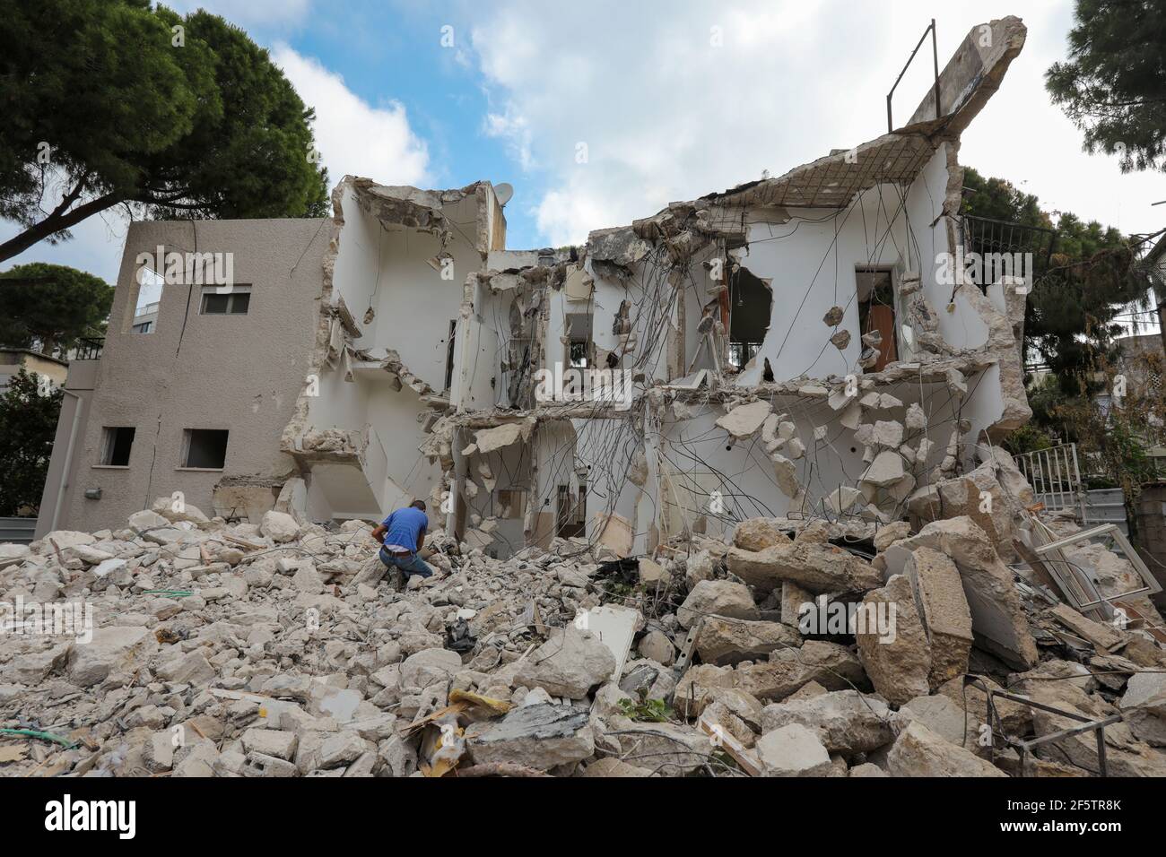 Mann kniet vor dem zerbrochenen Haus auf Ruine Abriss Ort nach der Zerstörung. Stockfoto