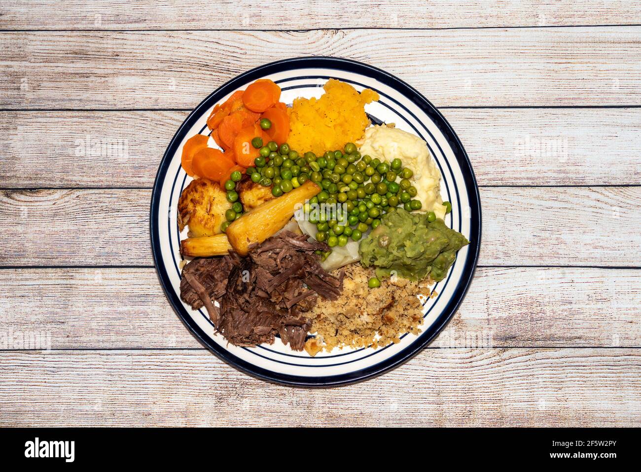 Sonntagabend mit langsam gekochtem, zerfetzten Rindfleisch auf einem Teller mit viel Gemüse wie Erbsen, Erbsen, Pastinaken, Bratkartoffeln und Karotten, Stockfoto