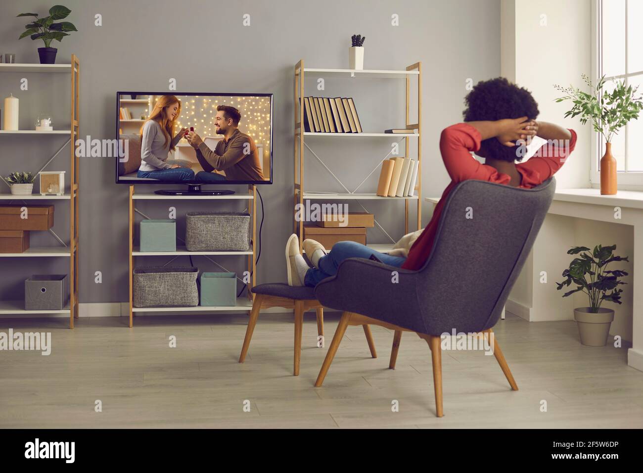 Entspannte Frau, die im Wohnzimmer auf einem Stuhl sitzt und Seife beobachtet oper im Fernsehen Stockfoto