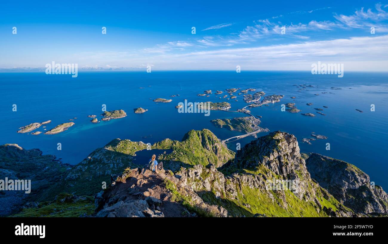 Kleine felsige Inseln im Meer, Wanderer blickt von der Spitze des Berges Festvagtind nach OrtHenningsvaer, Vagan, Lofoten, Nordland, Norwegen Stockfoto
