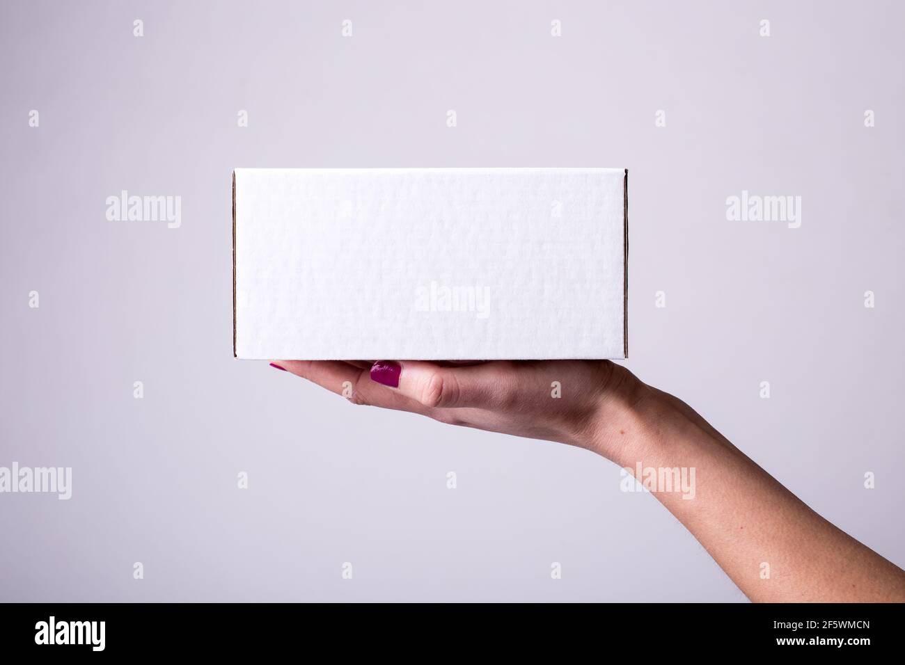 Weiße Pappschachtel in weiblichen Händen. Seitenansicht, Lieferung, Paket, Bestellung Stockfoto