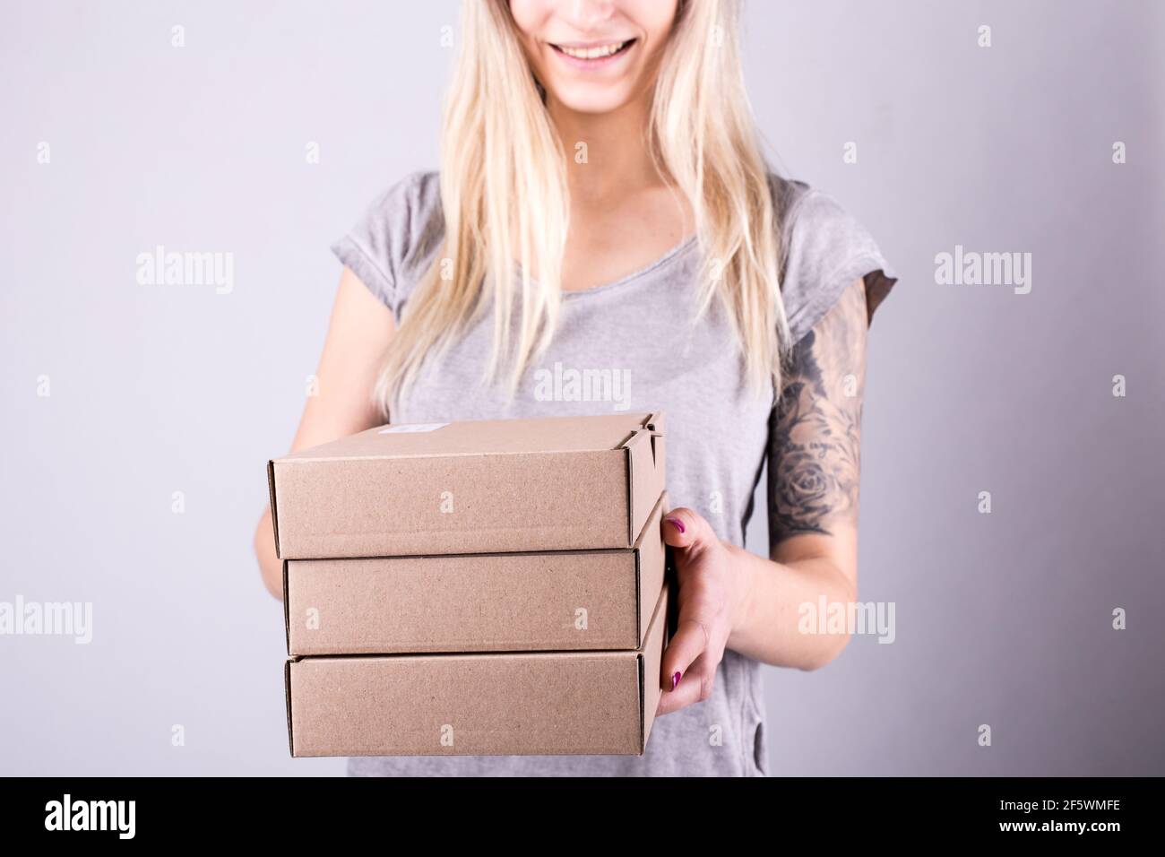 Junge Frau glücklich Lächeln hält Papierkartons in den Händen nein Gesicht Stockfoto