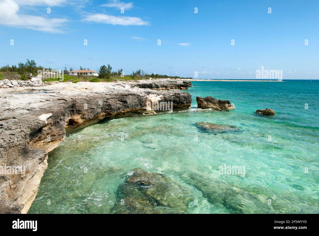 Der Blick auf Grand Bahama erodierte Ufer mit einem Wohnhaus im Hintergrund. Stockfoto