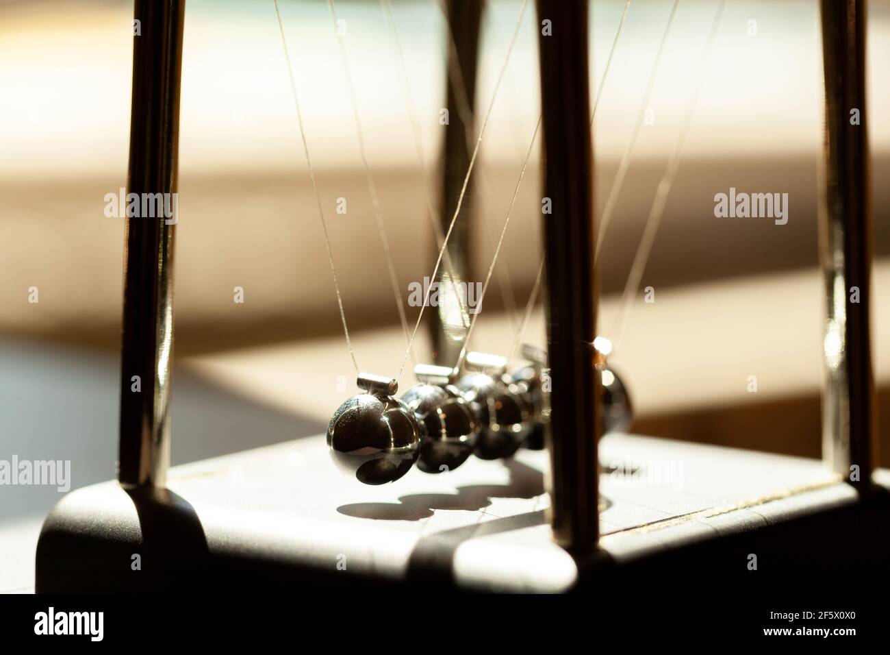 Klassische Newtons Wiege im Sonnenlicht, flacher dof, Metallkugeln noch Makro, extreme Nahaufnahme. Momentum, Bewegungsphysik und allgemeine physikalische Gesetze, einfach Stockfoto