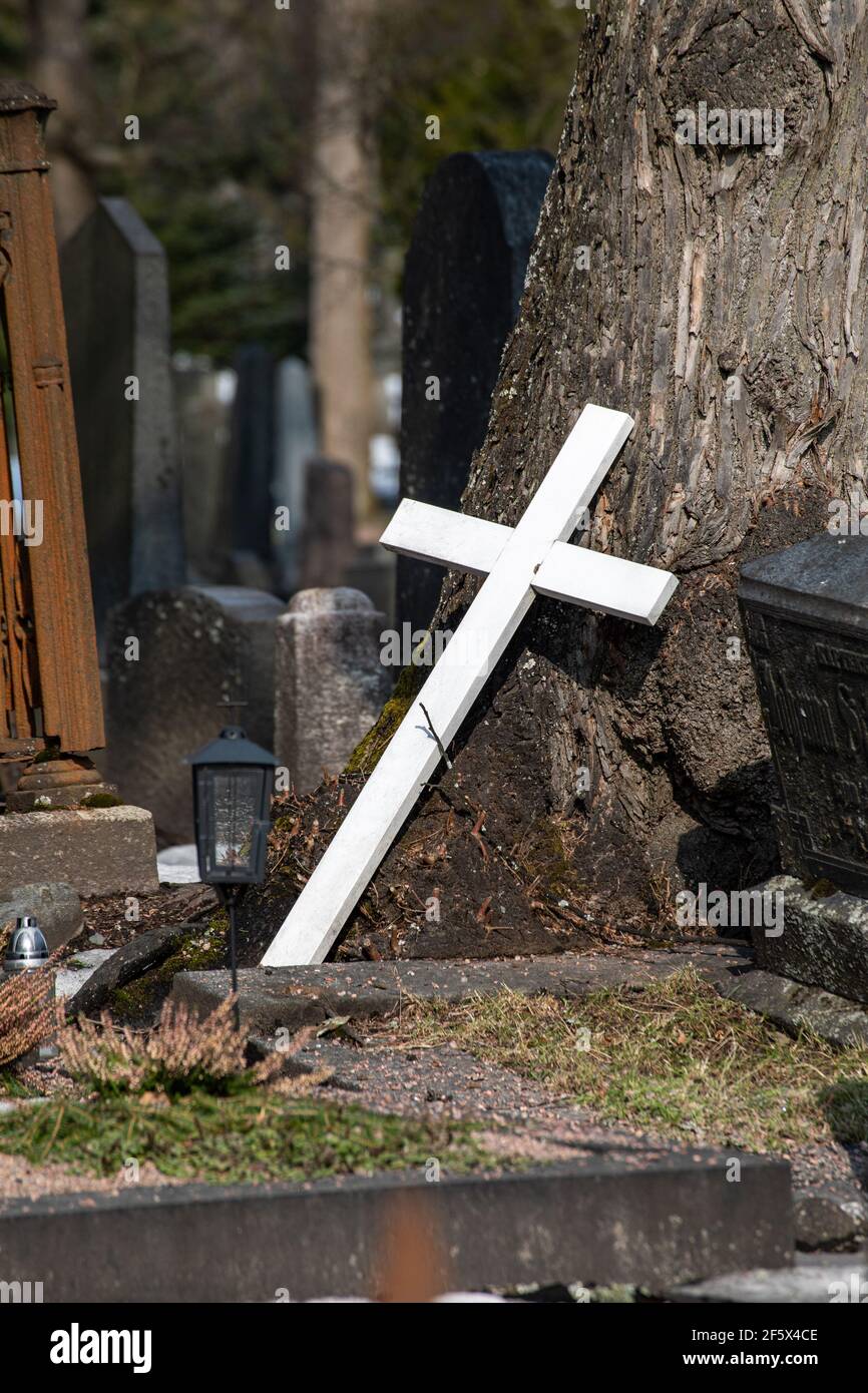 Weißes Holzkreuz am Baumstamm auf dem Friedhof von Hietaniemi in Helsinki, Finnland Stockfoto