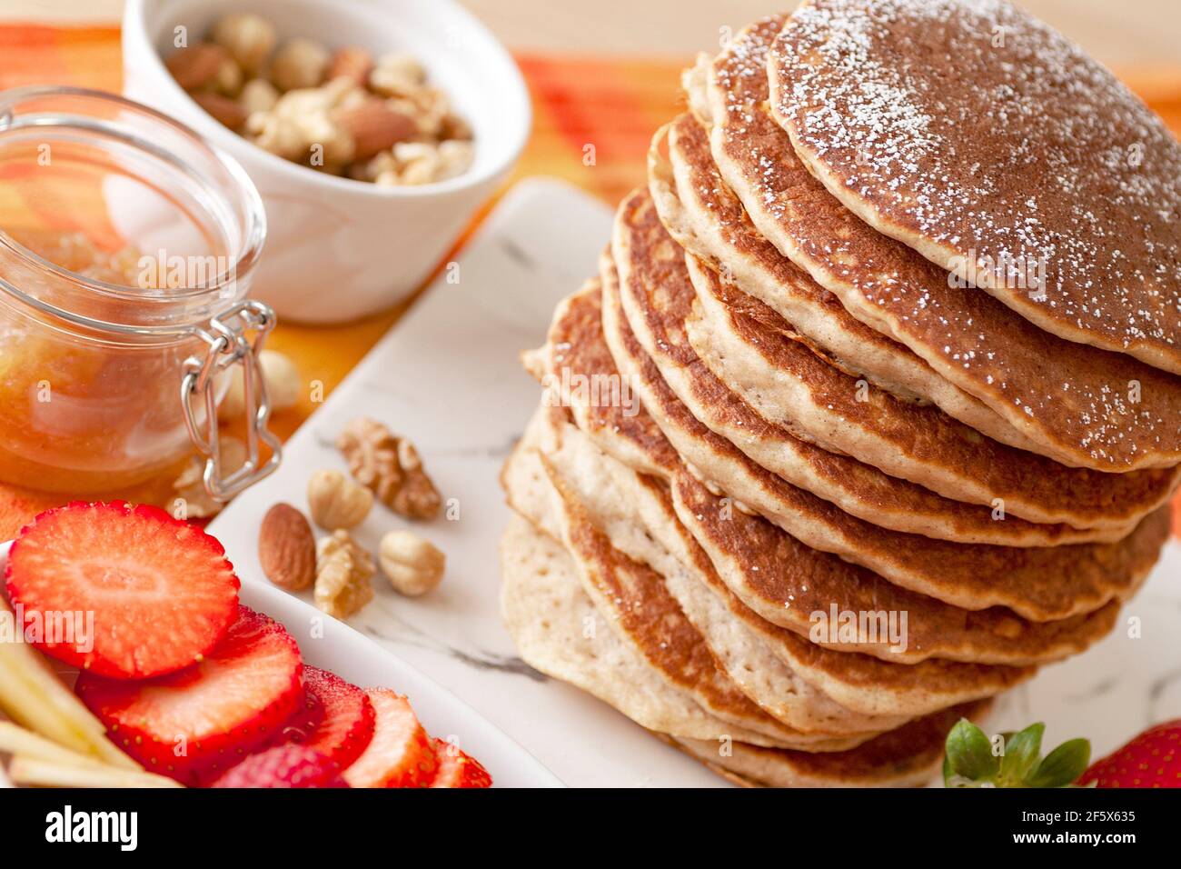 Pfannkuchen Turm mit Puderzucker und Obst. Erdbeeren, Äpfel, Nüsse und Marmelade. Stockfoto