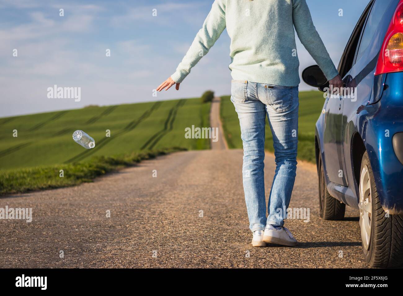 Fahrer wirft Plastikflasche auf der Straße. Plastikverschmutzung in der Natur. Stockfoto
