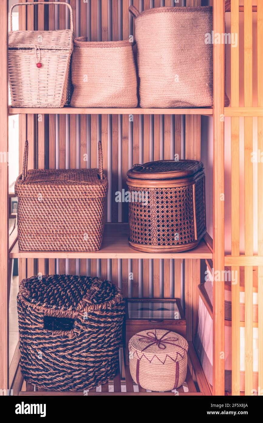 Feminine Boxen und Körbe aus natürlichen Materialien, in einem stilvollen Kleiderschrank, modische und elegante Inneneinrichtung gesetzt Stockfoto