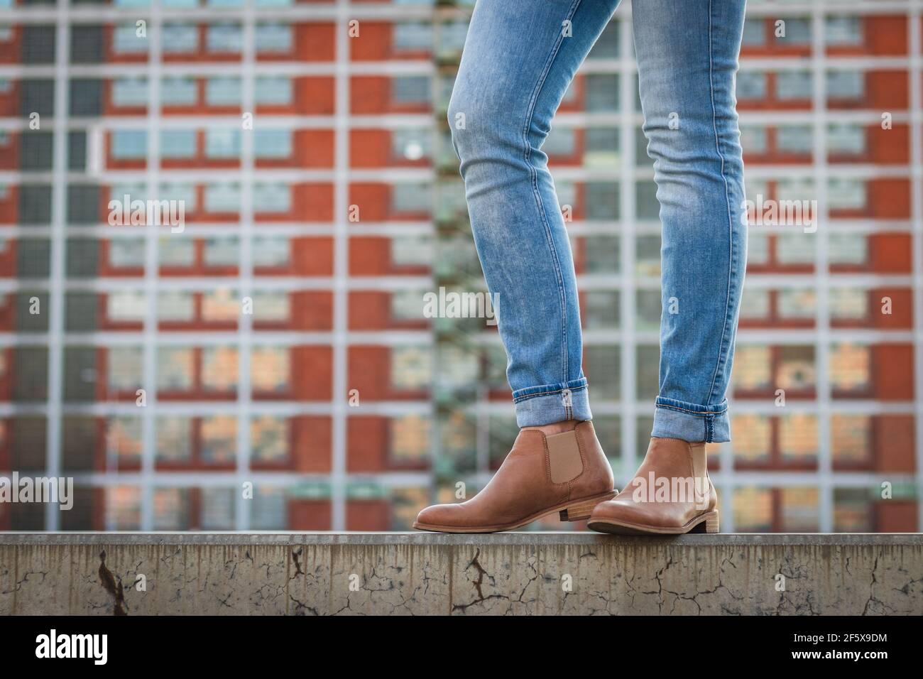 Modische schlanke Beine tragen Jeans und Lederschuhe in der Stadt. Moderne  Architektur als Hintergrund. Stilvolle Frau trägt legere Kleidung auf wa  stehen Stockfotografie - Alamy
