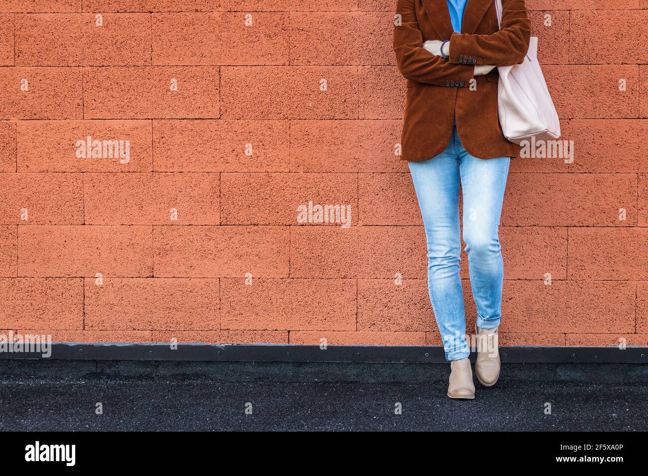 Frau in legerer Kleidung lehnte rote Backsteinmauer in der Stadt. Modekonzept mit Kopierraum Stockfoto