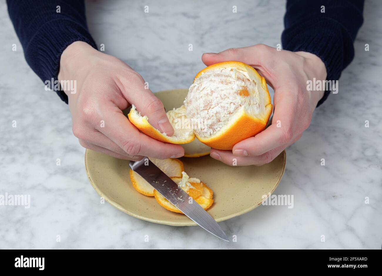 Die Hände des Mannes schälen eine Orange. Gesunde Ernährung Konzept Stockfoto