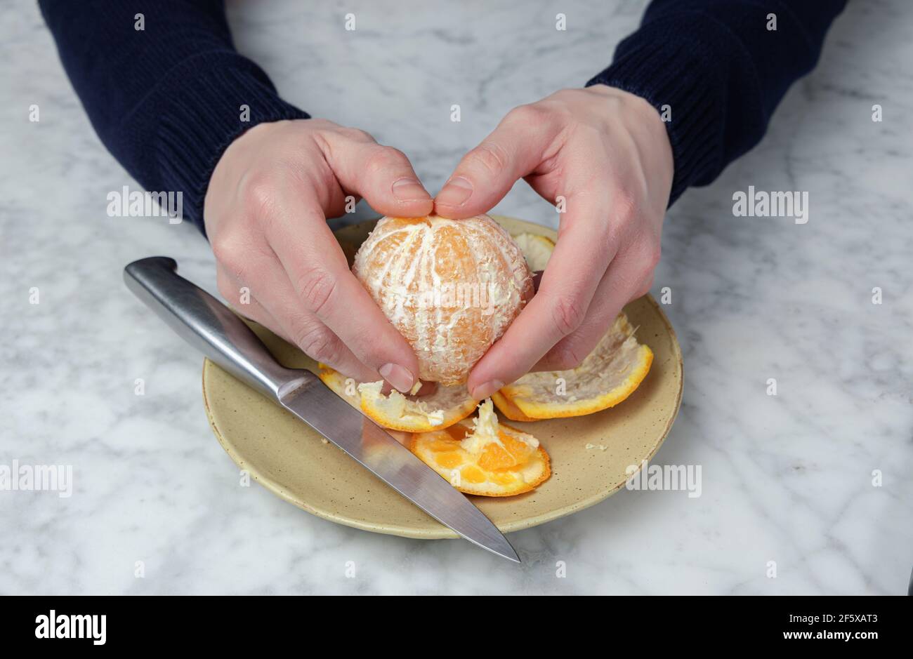 Die Hände des Mannes schälen eine Orange. Gesunde Ernährung Konzept Stockfoto