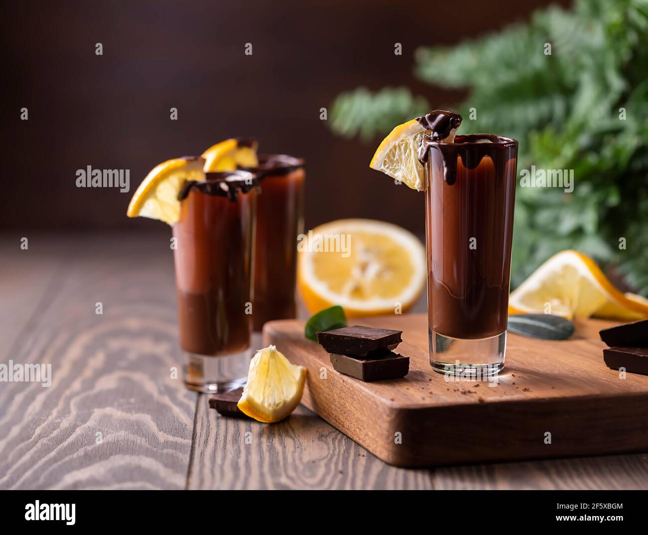 Cocktail in Schnapsglas mit Schokolade, Sahne-Likör, frischen Orangen auf dunklem Hintergrund. Hausgemachte Shot Drinks Party. Bar-Menü, Rezepte. Nahaufnahme, Auswahl Stockfoto