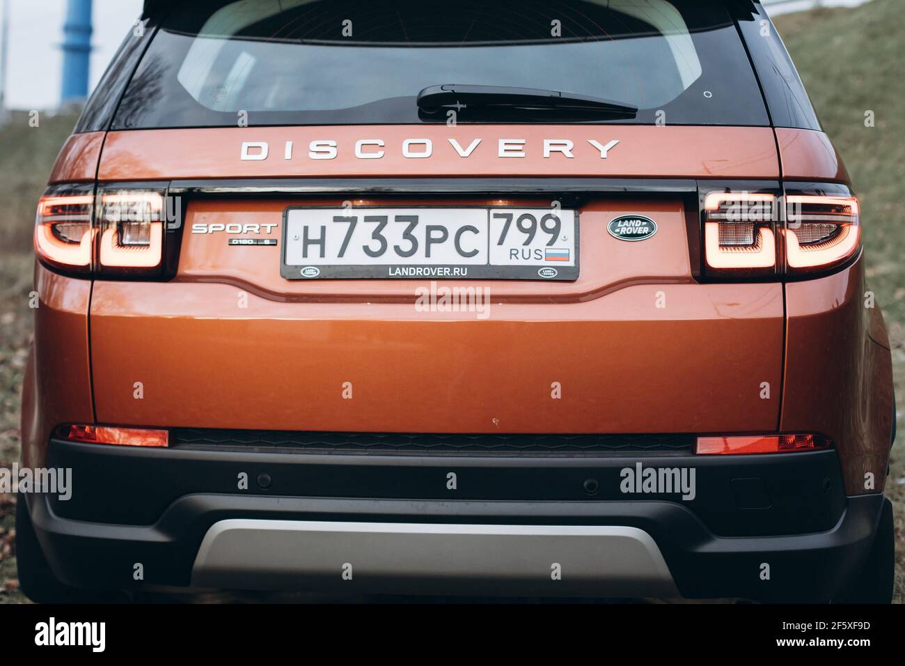 Moskau, Russland - 20. Dezember 2019: Rückansicht des neuen Premium england suv. Land Rover Discovery Sport im Wald geparkt. Orange Allradantrieb Auto steht auf dem Boden. Stockfoto