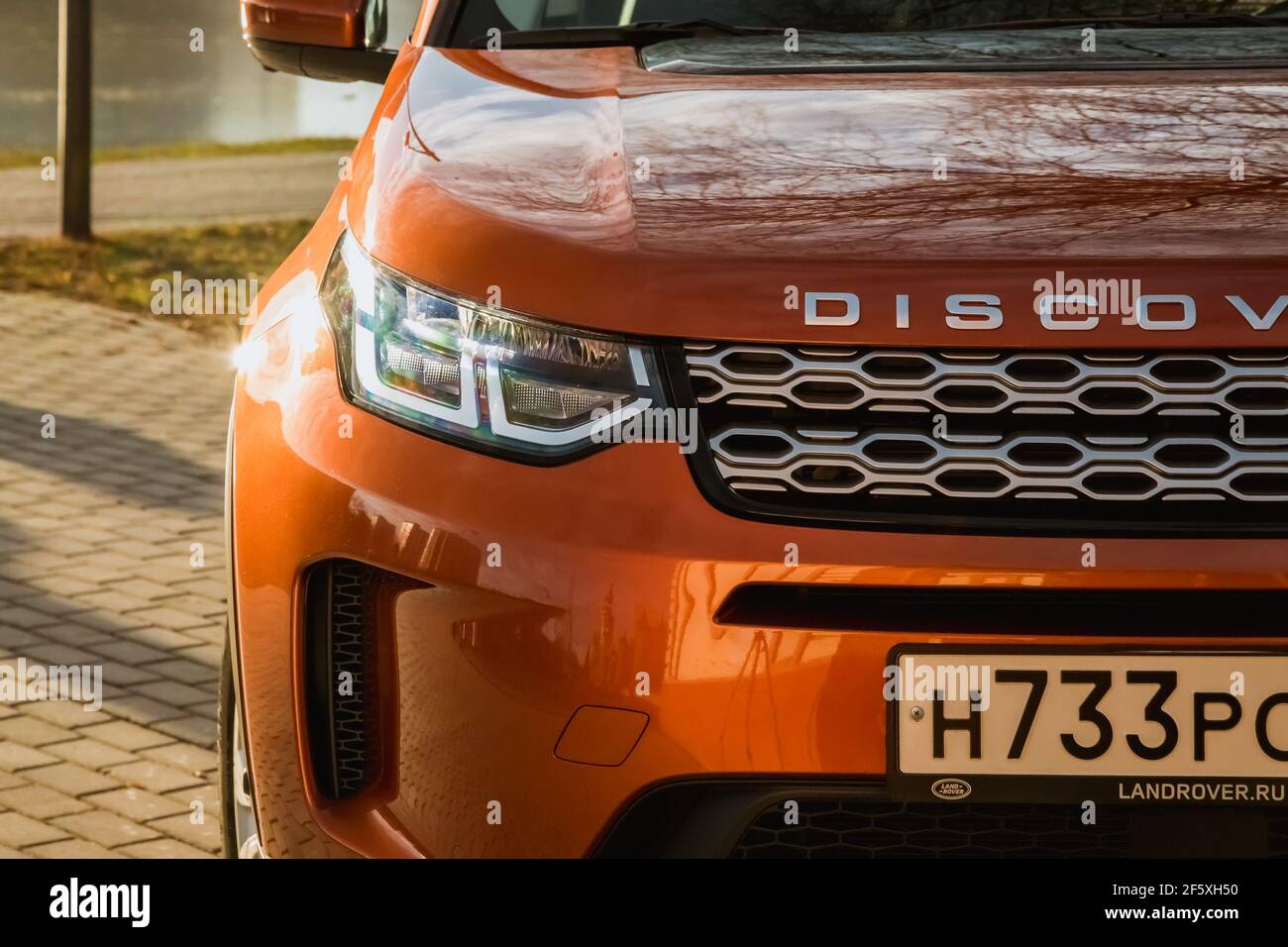 Moskau, Russland - 20. Dezember 2019: Der neue Land Rover Discovery Sport 2019 steht auf dem Park. Nahaufnahme der Vorderansicht. Scheinwerfer, Stoßfänger und Haube von orange suv.. Stockfoto