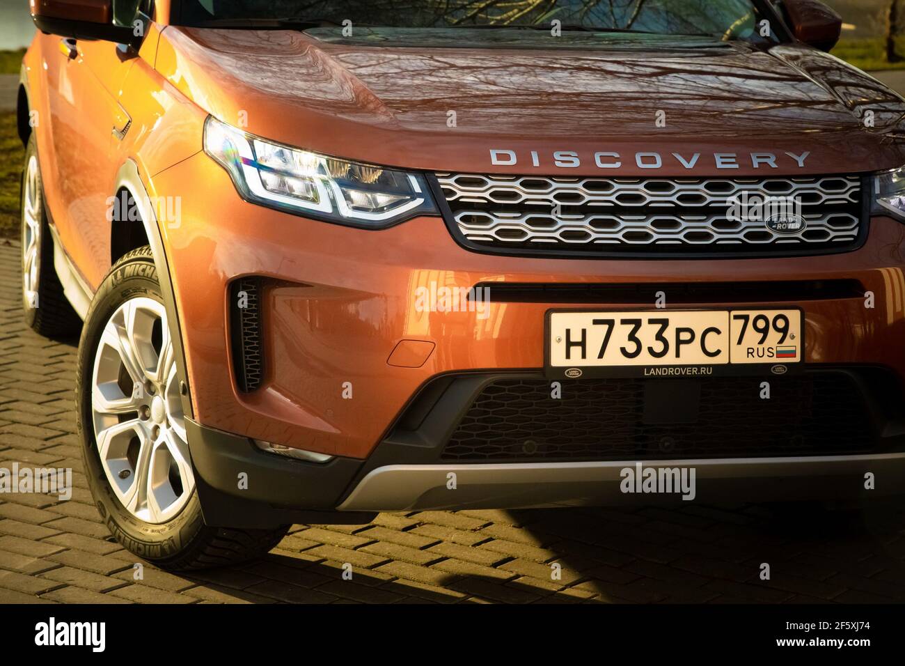 Moskau, Russland - 20. Dezember 2019: Der neue Land Rover Discovery Sport 2019 steht auf dem Park. Nahaufnahme der Vorderansicht der Seite. Scheinwerfer, Stoßfänger und Haube von orange suv, silberne Räder, .. Stockfoto