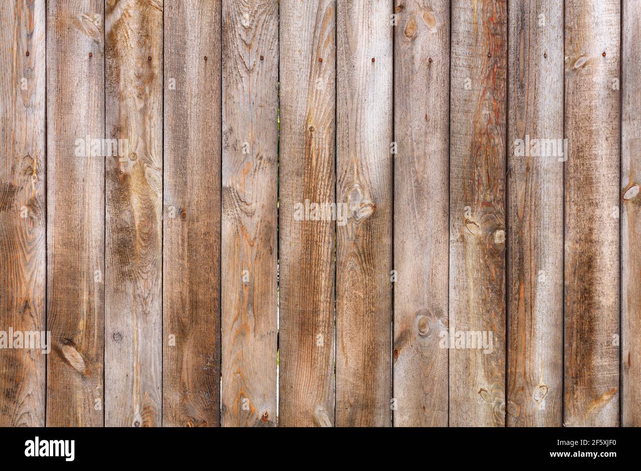 Ein einfacher und unlackierter Holzzaun aus unbehandeltem Holz mit einer rauen Textur und rostigen Nägeln. Stockfoto