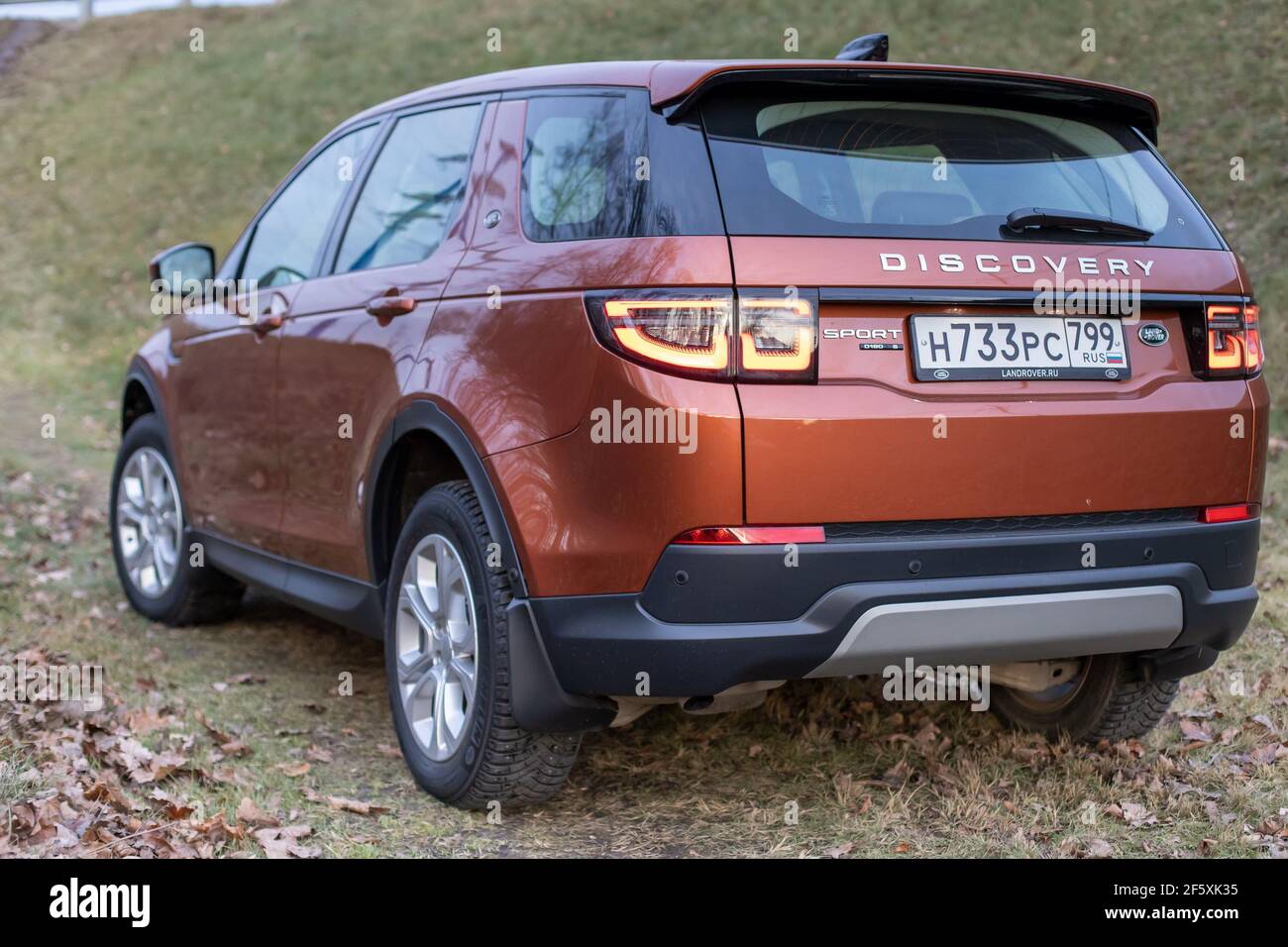 Moskau, Russland - 20. Dezember 2019: Rückansicht des neuen Premium england suv. Land Rover Discovery Sport im Wald geparkt. Orange Allradantrieb Auto steht auf dem Boden. Stockfoto