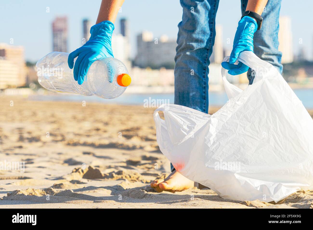 Sauberer Strand aus Kunststoff. Hand herauf Plastikflasche Papierkorb vom Strand und in Plastikbeutel für Recycling Stockfoto