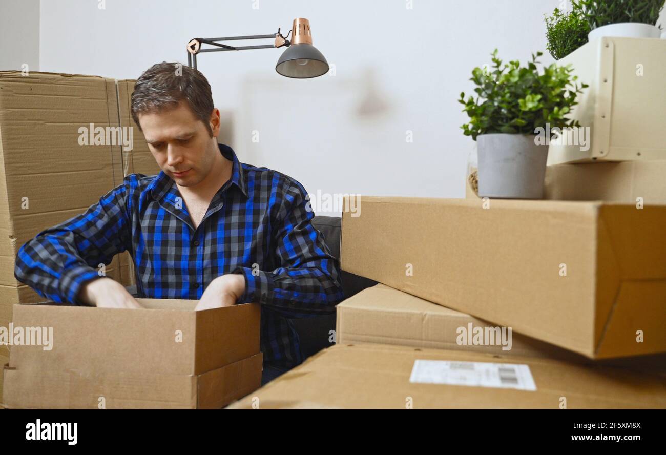 Mann, der sein Zeug in eine neue Wohnung auspackte. Stockfoto
