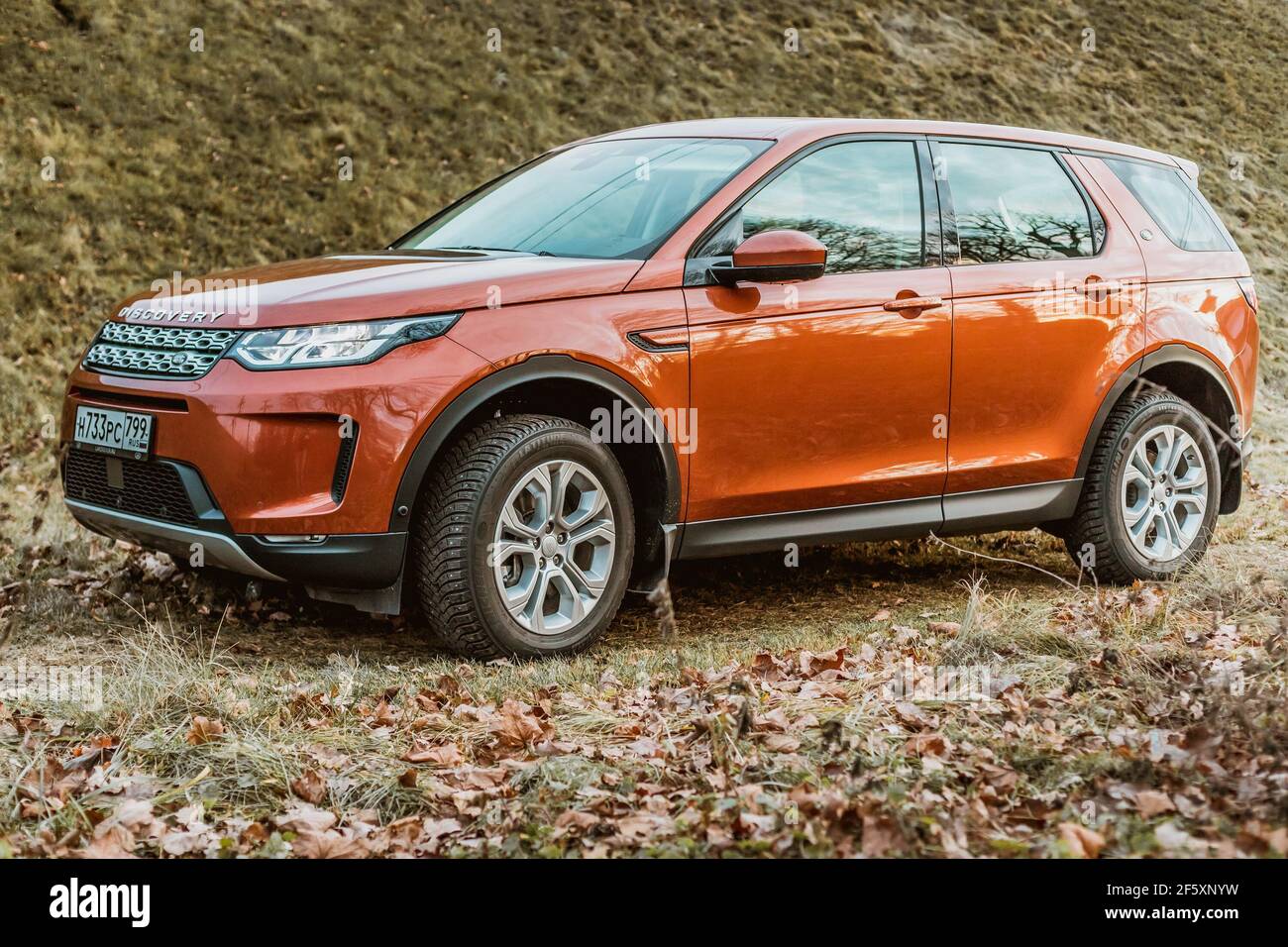 Moskau, Russland - 20. Dezember 2019: Seitenansicht des neuen Premium england suv. Land Rover Discovery Sport im Wald geparkt. Orange Allradantrieb Auto steht auf dem Boden. Stockfoto