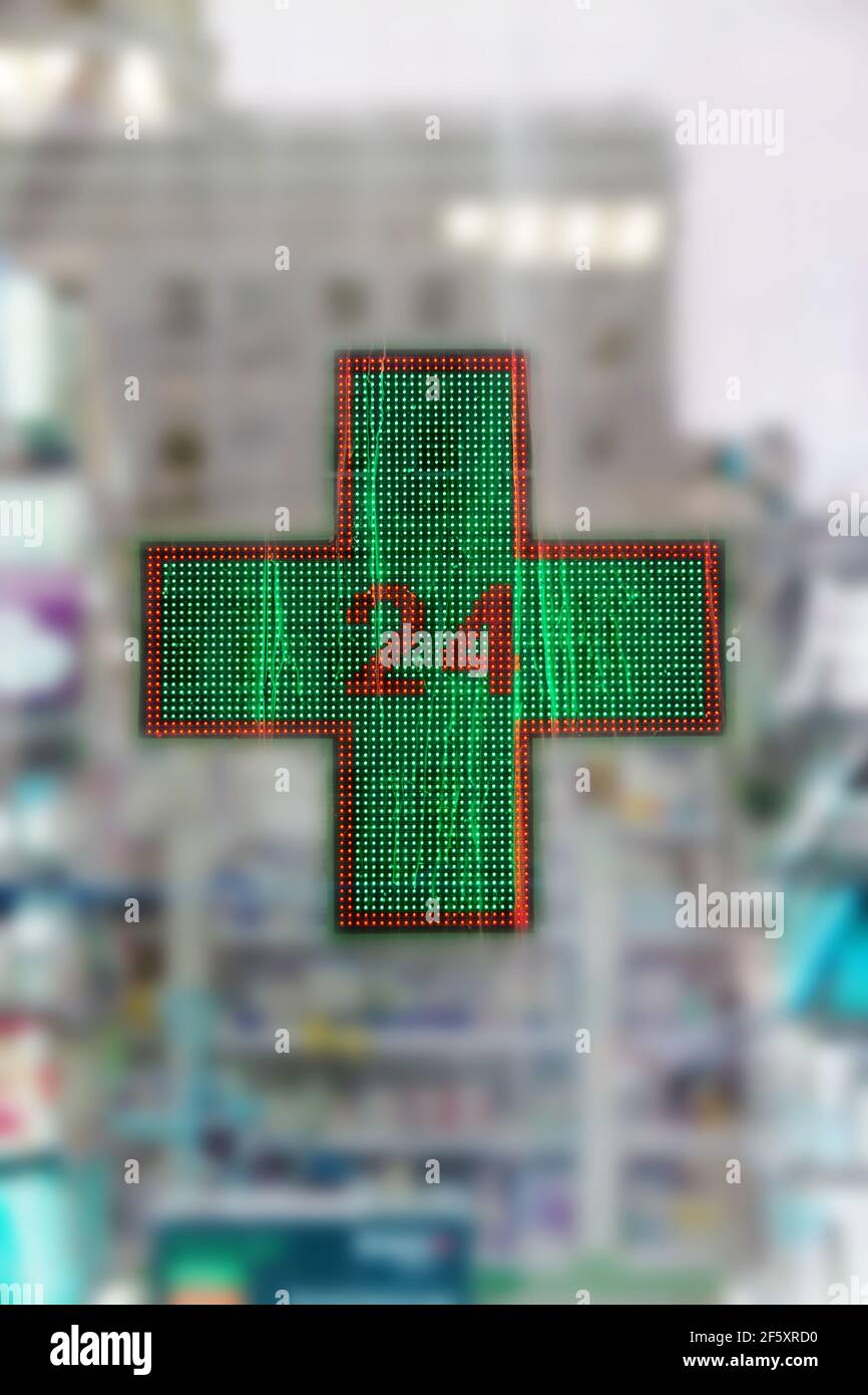 Apotheke leuchtendes Kreuz. Zeichen eines grünen medizinischen Kreuzes auf dem Hintergrund eines Drogerievorladens Stockfoto
