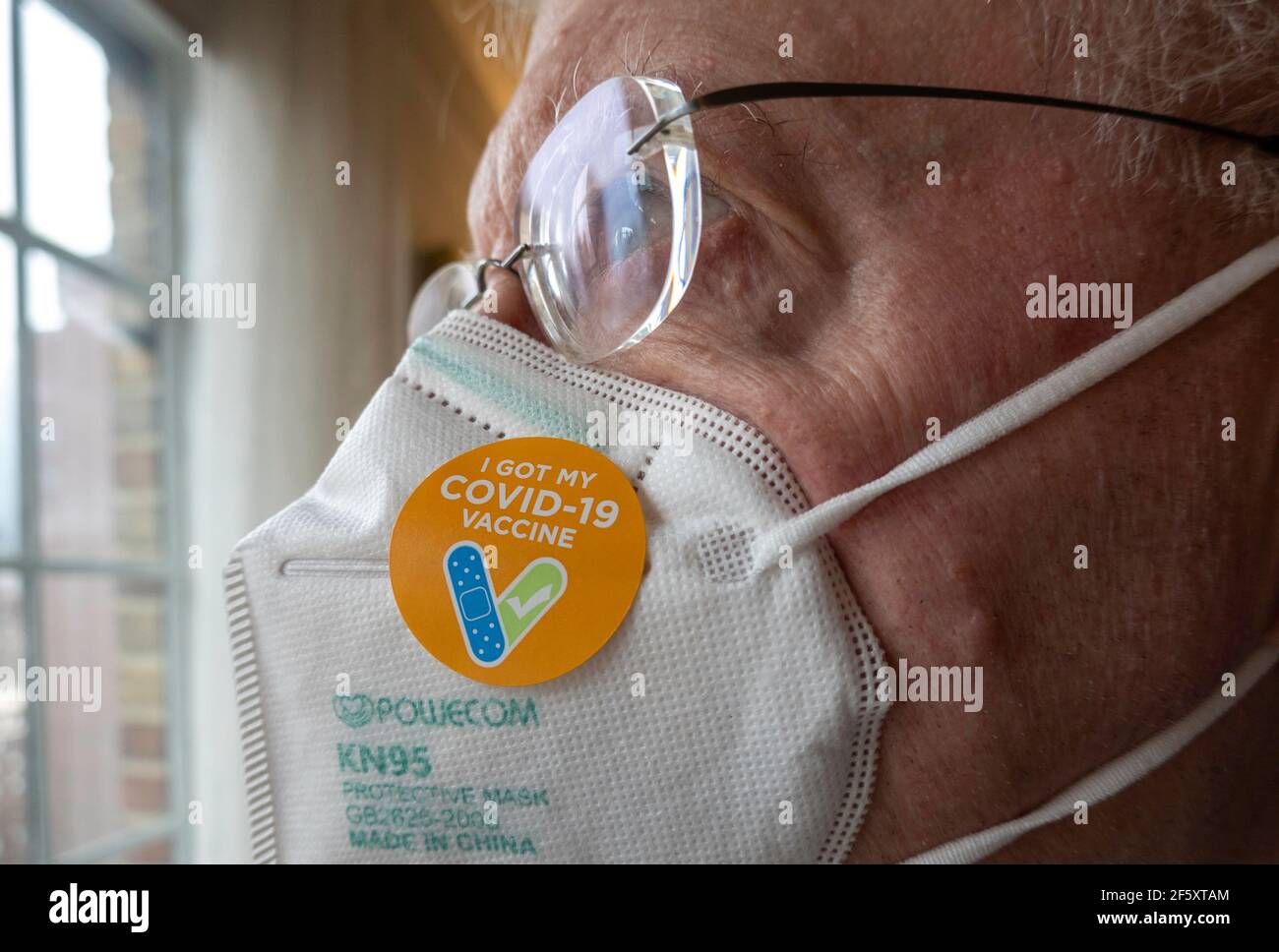 Älterer Mann mit dem Aufkleber „Ich habe meinen COVID-19-Impfstoff“ auf seiner Schutzmaske KN95, USA Stockfoto
