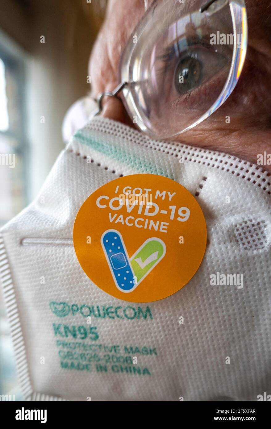 Älterer Mann mit dem Aufkleber „Ich habe meinen COVID-19-Impfstoff“ auf seiner Schutzmaske KN95, USA Stockfoto