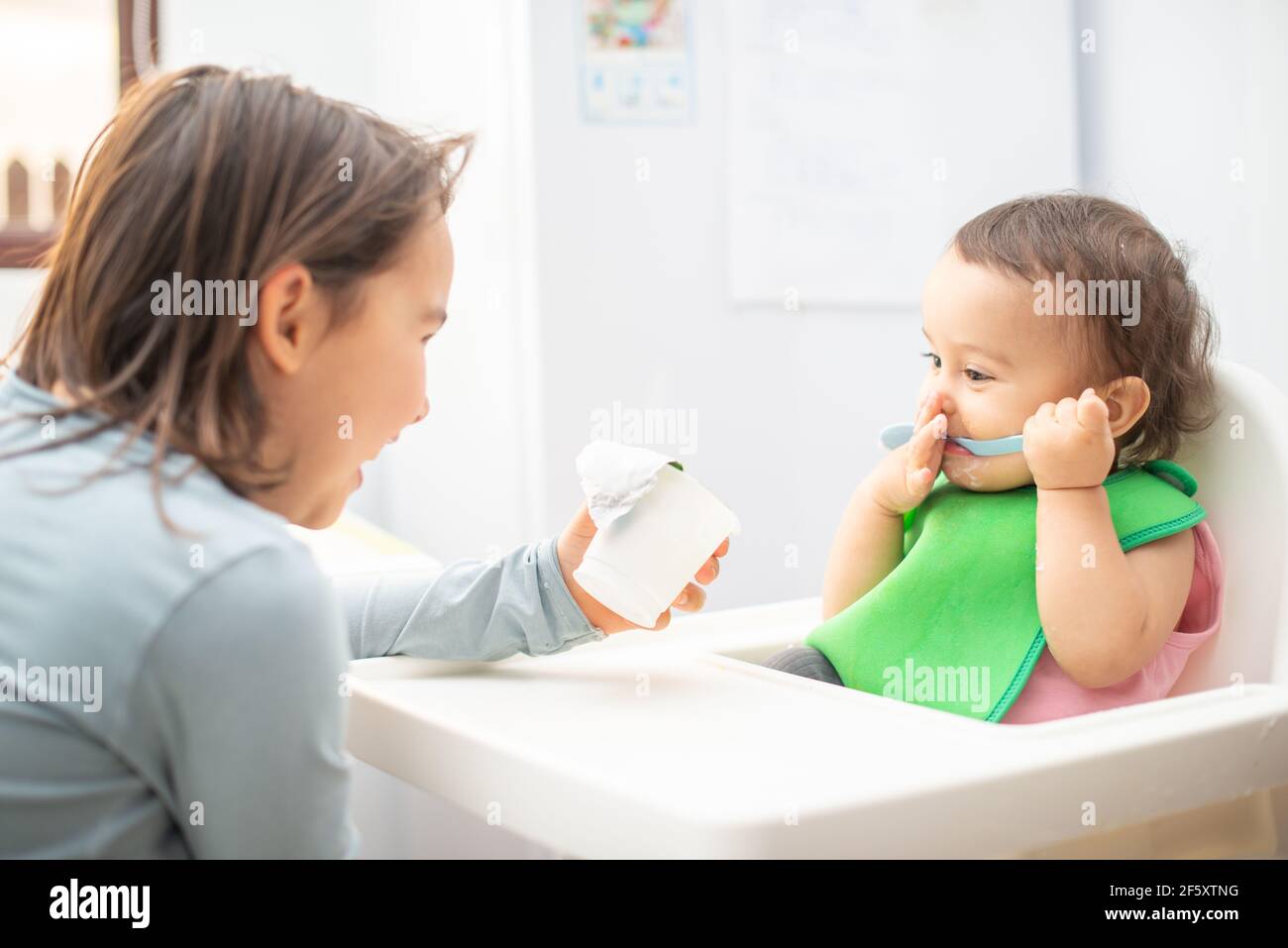 Ältere Schwester füttern ihre jüngere Schwester und Spaß haben. Stockfoto