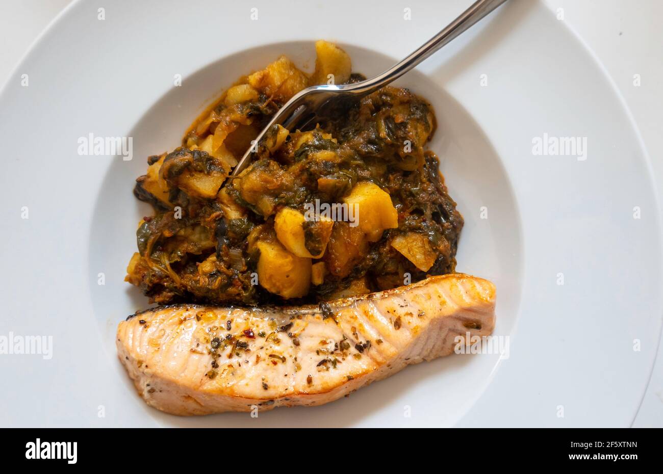 Gegrilltes Lachsfilet mit saag und Aloo (Spinat und Kartoffeln) Stockfoto