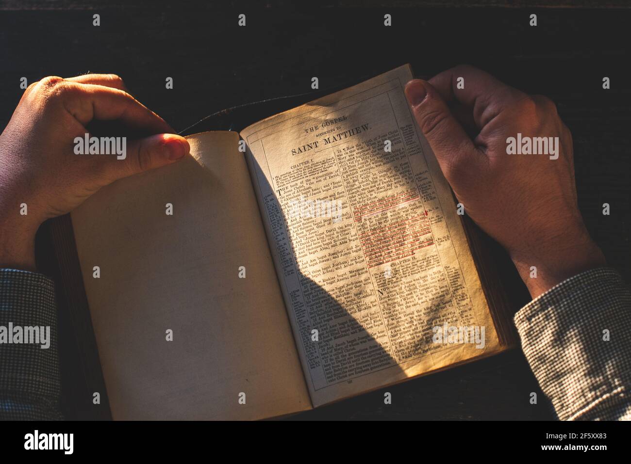 Gebet, Mann übergibt ein altes offenes Buch Heilige Bibel, Holzschreibtisch Hintergrund. Stockfoto