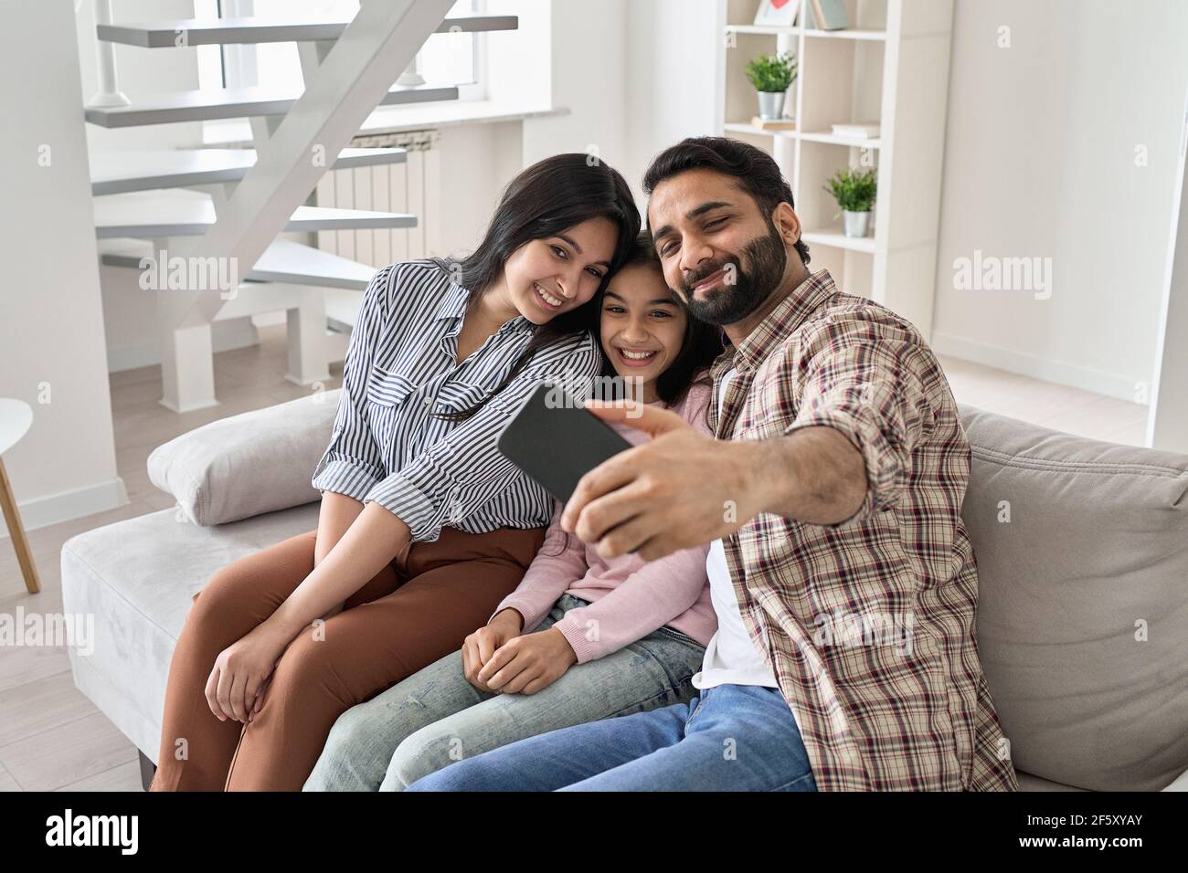 Glücklich indisch Familie mit teen Tochter mit Spaß nehmen Selfie am Telefon zu Hause. Stockfoto