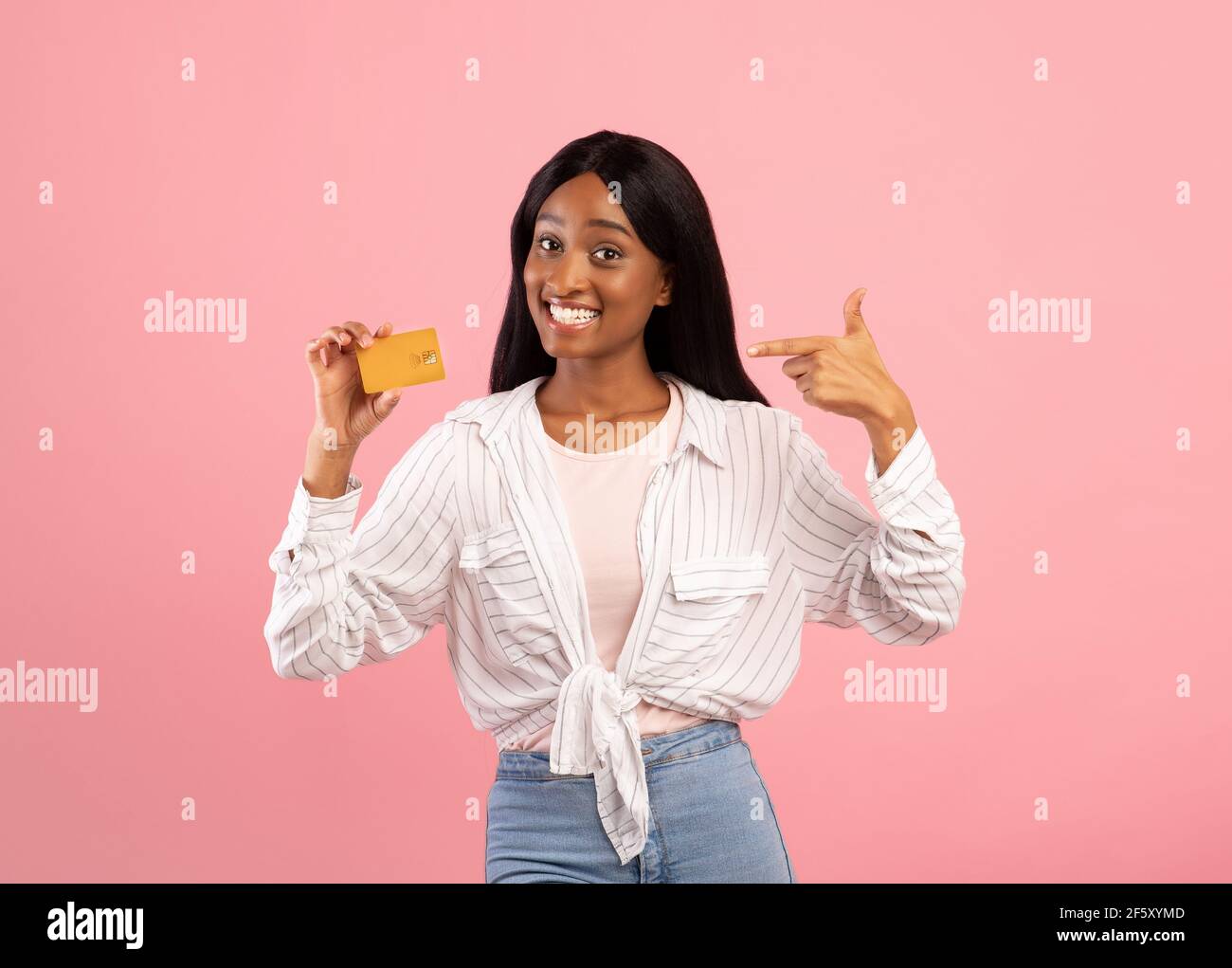 Kontaktloses Shopping-Konzept. Fröhliche schwarze Frau zeigt auf Kreditkarte mit einem Lächeln auf rosa Studio Hintergrund Stockfoto