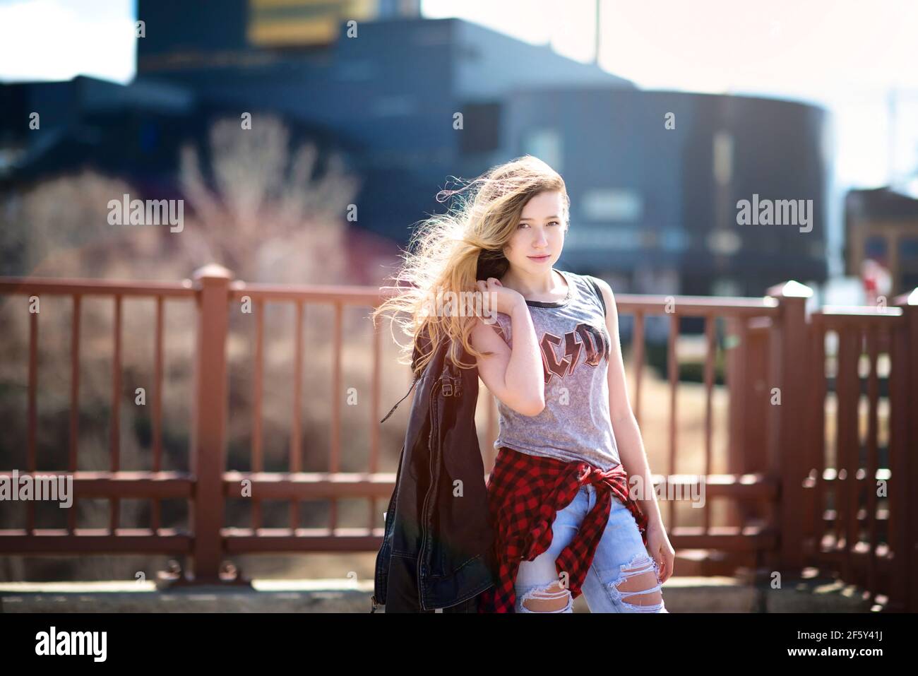 Teen Mädchen mit langen Haaren hält Lederjacke in städtischen Umgebung. Stockfoto